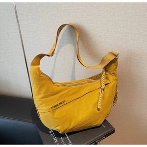 Detail of a bright yellow crescent nylon shoulder bag featuring the THREE TREES letter print