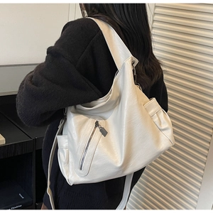 Detail view of large cream PU tote with side pockets and vertical zipper on model