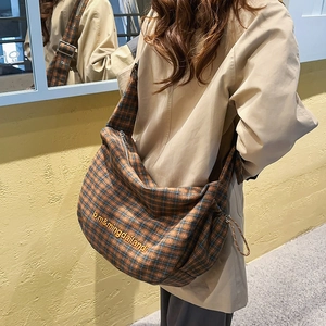 Detail of vintage brown and blue plaid canvas tote bag featuring embroidered text