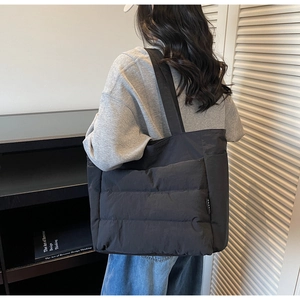 Close-up of black quilted puffer tote bag with wide strap for casual daily commuting
