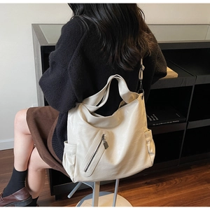 Detail of minimalist beige tote bag with wide strap and zip pocket in a cozy setting