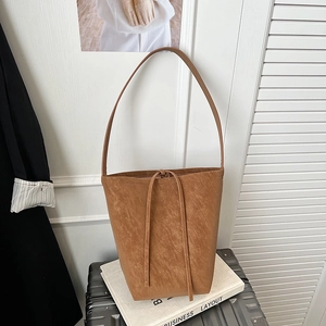 Detailed close-up of brown faux leather bucket bag texture on white books and case