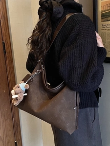 Vintage brown embossed floral tote bag with a cute bear charm in a stylish commute setting