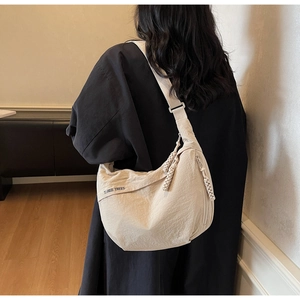 Detail of beige nylon crossbody bag with black Three Trees embroidery and wide strap