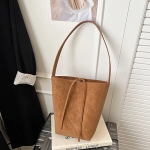 Close-up of a brown retro bucket bag with fine leather texture and drawstring detail