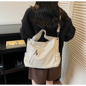 Back view of model wearing a large cream tote bag to show size and fit on the body