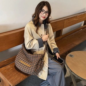 Detail of checkered canvas shoulder bag with yellow embroidery in a cozy cafe setting