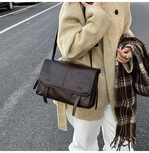 Close-up of retro dark brown textured faux leather shoulder bag with buckle details