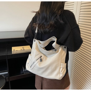 Detailed view of cream white leather tote bag showing side pockets and smooth texture