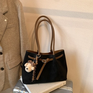 Detail view of retro tote bag with black matte finish and brown leather straps on luggage