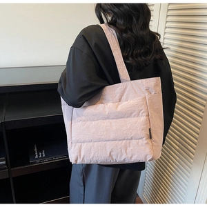 Detail of light pink quilted tote bag with side pocket and soft padded texture