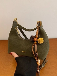 Dark green minimalist dumpling bag with golden zipper and vintage beaded tassel charm