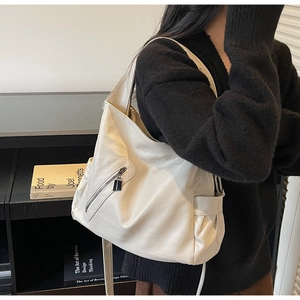 Close-up of creamy white faux leather shoulder bag with functional side pocket detail