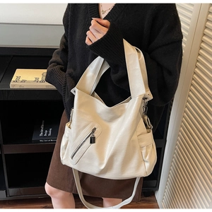 Detail showing soft lychee-patterned cream faux leather and decorative front zipper pocket