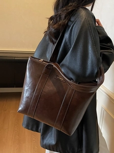 Sac fourre-tout marron foncé en similicuir porté par un mannequin en intérieur