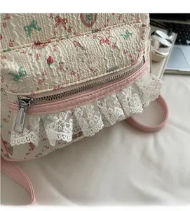 Gros plan du sac à dos crème avec motifs floraux matelassés et détails en dentelle rose