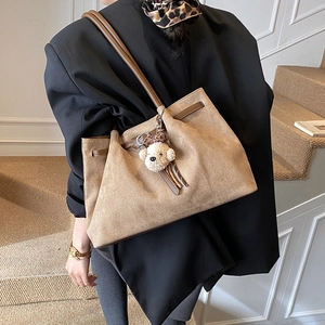 Detail of a large vintage brown suede tote bag with a cute plush dog charm on the strap