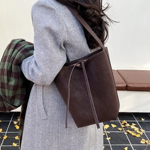 Close-up of retro dark brown suede bucket bag with leather strap detail for women