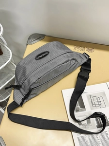 Gray checkered crossbody sling bag with adjustable strap on a minimalist desk