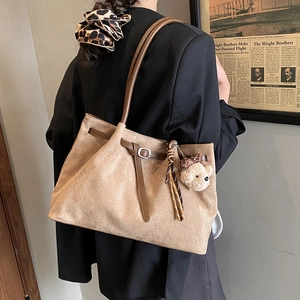 Detail of light brown faux suede tote bag with slim shoulder straps and bear keychain