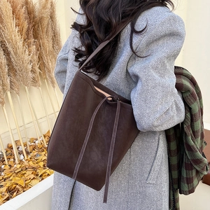Detail of dark brown suede bucket bag with drawstring and vintage matte finish