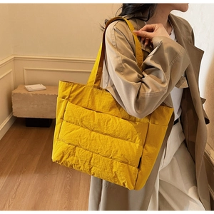 Detail of a bright yellow quilted tote bag showing waterproof texture and side pocket