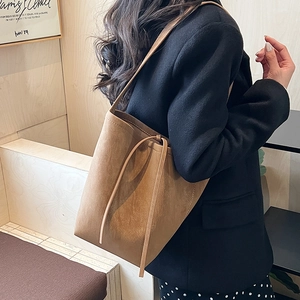 Close-up of retro brown suede bucket bag with slender drawstring detail and soft texture
