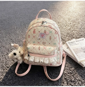 Détail du sac à dos imprimé lapin avec bordure en dentelle et porte-clé chien peluche