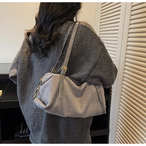 Detail view of grey suede shoulder bag with gold metal eyelets and premium texture