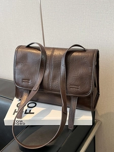 Vintage dark brown PU leather crossbody bag with flap closure on minimalist background