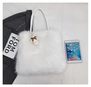 Close-up of fluffy white faux fur tote bag with a bear charm showing the actual size