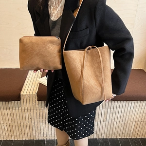 Detail of earthy brown matte leather bucket bag with matching zipper pouch on model