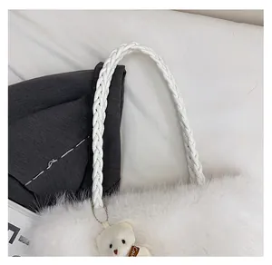 Close-up of white plush handbag featuring a woven PU handle and a cute bear pendant