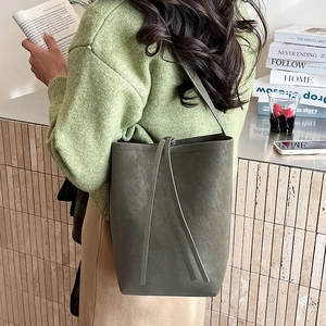 Olive green bucket bag in matte leather texture shown with a stylish casual outfit