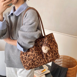 Detailed close-up of leopard print tote bag with brown leather handles and plush bear charm