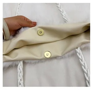 Detail of white plush handbag featuring gold magnetic buckle and woven rope handle strap