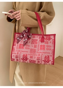 Détail d'un sac cabas de mariée rouge avec motif Double Bonheur et décoration en foulard de soie
