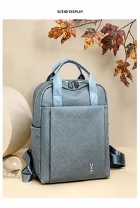 Detailed view of light blue business backpack with leaf decor and front pocket