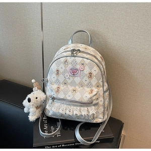 Détail d'un sac à dos matelassé crème avec imprimé ours et bordure en dentelle
