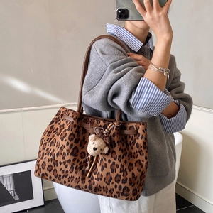 Shoulder shot of large leopard print tote bag with cute plush bear pendant accessory