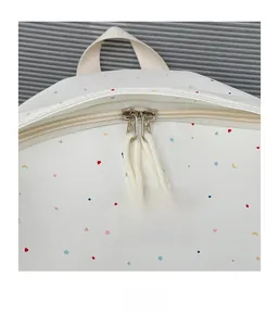 Detailed macro view of the smooth metal double zipper on the white starry canvas backpack