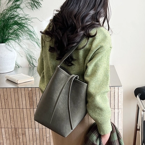 Close-up of matte olive green bucket bag with fringe tassels and soft suede texture