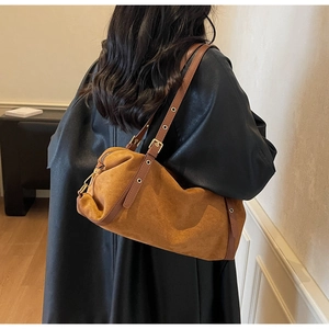 Detail of brown suede cylinder shoulder bag with adjustable strap and metal eyelets