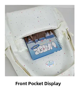Detailed view of white polka dot backpack front pocket with a notebook inside