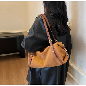 Detail of caramel suede shoulder bag showing textured material and adjustable gold buckle