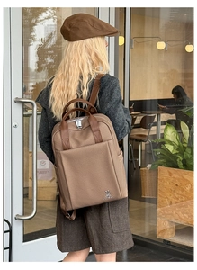Close-up of brown canvas business backpack with leather trim and silver rabbit logo detail