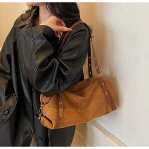 Brown suede bucket bag detail showing the long leather strap and metallic eyelet design