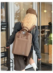 Outdoor lifestyle shot of a brown woven business backpack with metal rabbit logo detail