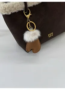 Detail of suede bucket bag with lamb wool trim and decorative glove charm on metal chain