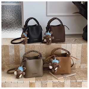 Détail de sacs seaux en quatre couleurs avec poignées tressées et breloques en peluche